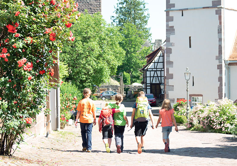 fünf Kinder laufen nebeneinander auf einer Kopfsteinpflasterstraße